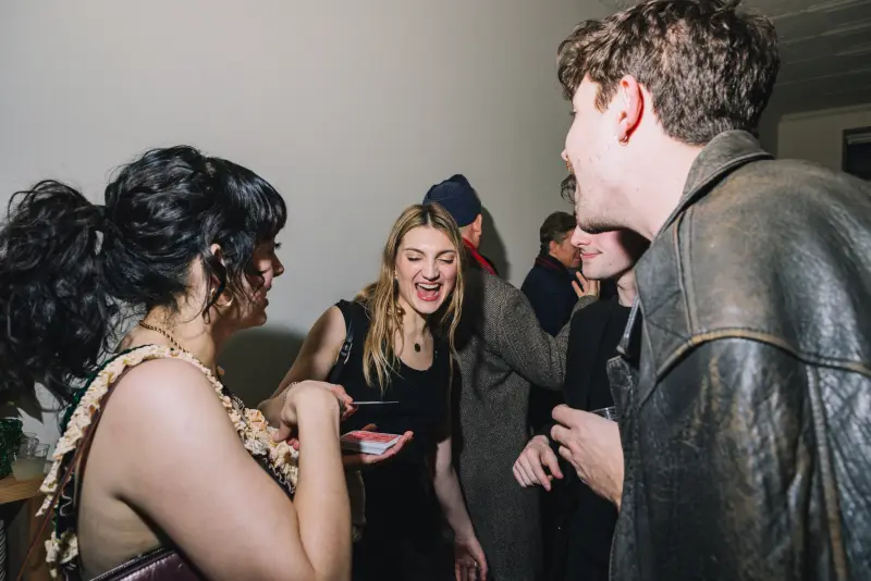 A guest laughing in disbelief while holding a playing card