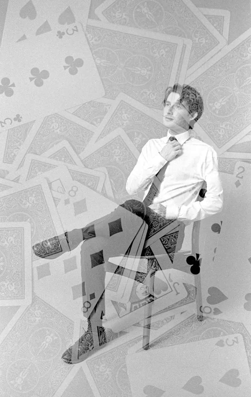 Black and white double exposure of Jacob seated in a chair, layered with scattered playing cards