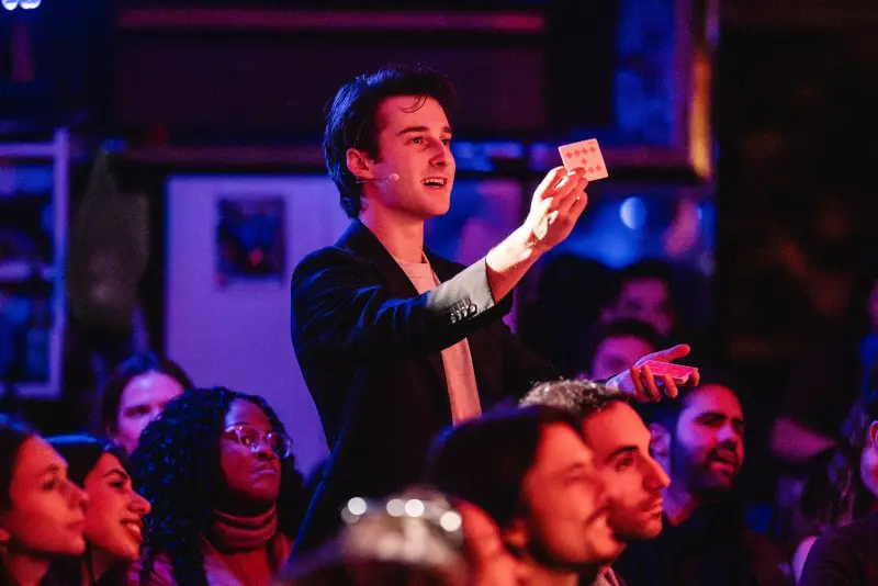 Jacob on stage holding up a playing card in front of an audience