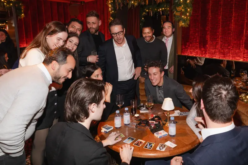 Guests crowded around a table laughing as Jacob performs close-up magic